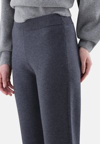 Graue Strickhose mit einer glatten Textur und elastischem Bund. Gerades Bein Design mit Seitennähten, ergänzt durch einen grauen Pullover darüber.