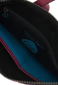 Interno nero con una vivace fodera blu, dotato di un scomparto con zip e rifiniture in pelle bordeaux. Etichetta con la dicitura "Made in Italy."
