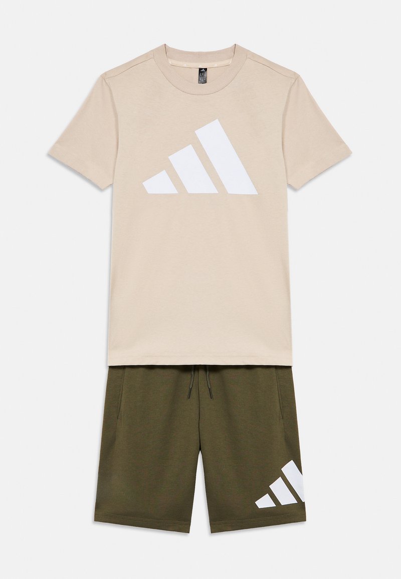 Camiseta de algodón beige con un gran logo triangular blanco, combinada con pantalones cortos verde oliva que presentan un logo a juego en el lateral.