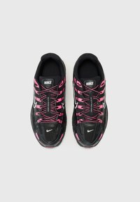 Schwarze Sportschuhe mit rosa Akzenten und Schnürsenkeln, die eine strukturierte Oberseite, Netzeinsätze und eine abgerundete Zehenpartie aufweisen. Nike-Logo auf der Zunge und an der Seite.