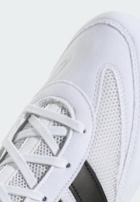 Weißer Sneaker mit strukturiertem Stoffobermaterial, Mesh-Einsätzen und grauen Lederakzenten. Er verfügt über flache Schnürsenkel und gestickte Details.