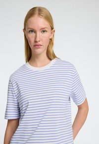 Vit t-shirt med tunna blå ränder, korta ärmar och rundad halsringning. Mjuk textur, avslappnad passform och minimal detaljer.