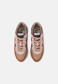 Zapatillas marrones y rojas con material de malla y ante, puntera redonda, cordones crema y suela de goma. Presenta un logo en la lengüeta y un diseño transpirable.