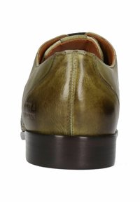 Scarpa verde in pelle con una texture liscia, forma arrotondata e suola marrone. Presenta dettagli di cucitura e un logo leggermente impresso.