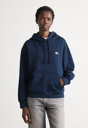 Felpa con cappuccio blu navy, tasca frontale, cappuccio con cordini e un piccolo logo sul petto. Realizzata in un tessuto morbido con polsini a coste.