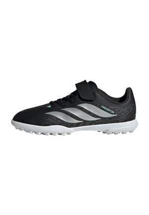 Crampon de football Adidas Predator noir et blanc avec bride velcro, semelle texturée et trois bandes argentées sur le côté.
