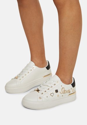 Hvide sneakers med plateau-sål, gyldne snørehuller, sorte hæl-accenter og dekorative guldfarvede perleornamenter, der danner ordet "love" på benene.