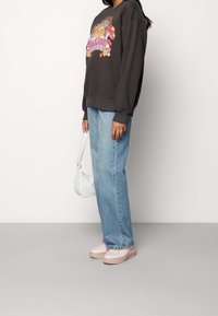 Sudadera gris con un gráfico colorido, jeans rectos azules, zapatos rosas y un bolso de hombro azul claro. Conjunto casual con materiales suaves.