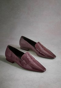 Burgundy patent leather loafers with a pointed toe, slip-on design, and flat heel. Features a raised band across the vamp.