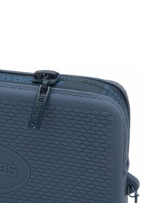 Borsa a tracolla blu navy con superficie testurizzata e motivo. Presenta una cerniera nera e un'etichetta con il nome del marchio chiaramente visibile.