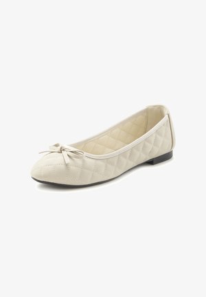 Bailarina de color beige acolchada con puntera redonda, que presenta un pequeño lazo decorativo, parte superior de tela y suela plana de goma. Superficie texturizada.