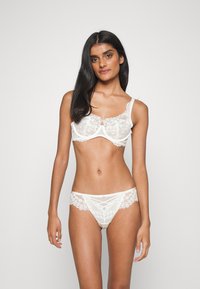 Weißes Spitzen-BH- und Slips-Set mit transparenten Einsätzen, floralen Mustern, verstellbaren Trägern und zarten Borte-Details. Weicher Stoff.