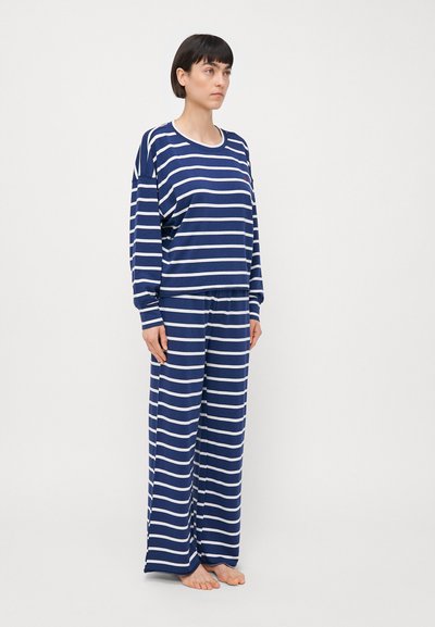 Pajamaset v navy in belih trakah, izdelan iz mehkega blaga, z dolgimi rokavi in širokimi hlačami za sproščen fit.