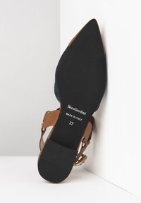 Suela negra con agarre texturizado, detalles en tira de cuero marrón y diseño de punta afilada. Marcado con "NeroGiardini" y talla 37. Fabricado en Italia.