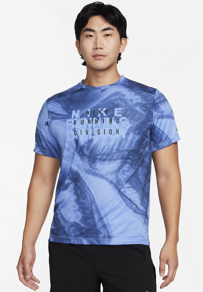 T-shirt de sport bleu avec un motif graphique dans des nuances de bleu variées, avec "NIKE RUNNING DIVISION" imprimé en noir de manière bien visible.