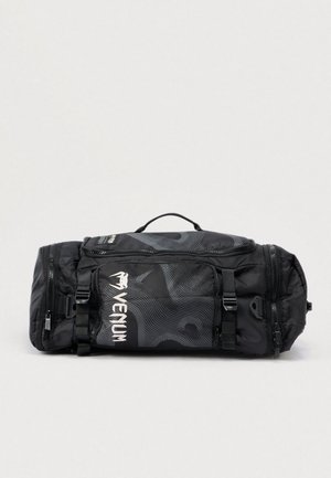 Juoda duffel tipo kuprinė su lygiu paviršiumi, puošta stilizuotu geometriniu raštu, logotipu, dviem užtrauktukais ir reguliuojamomis petnešomis.