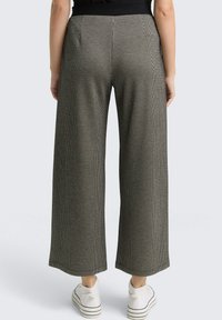 Brede broek in een textuurpatroon van zwart en wit, met een hoge tailleband en ontworpen met achterzakken.