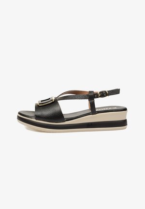 Sandalia negra de cuero con empeine abierto y tira trasera, detalle de hebilla dorada y suela plataforma gruesa en beige y negro.