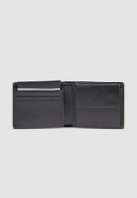 Black leather bifold wallet open to show card slots and a coin pocket on a plain light gray background.