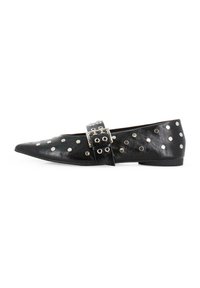 Bailarinas de cuero negro con punta afilada, con taches plateados y una correa con hebilla en la parte superior. Textura suave con un tacón bajo.