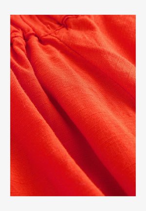 Červená ľanová tkanina s textúrovaným povrchom, zdobená zhrnutím. Tkanina vykazuje bohatú, živú farbu a jemnosť.