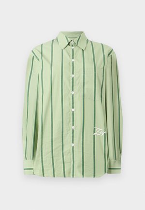 Chemise à manches longues vert clair avec des rayures verticales vert foncé, boutons blancs, poche sur la poitrine et texte brodé en blanc près de l'ourlet.
