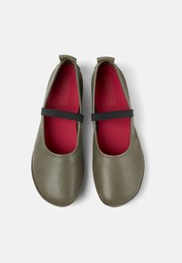 Zapatos de cuero verde con puntera redonda, plantilla roja y tira elástica negra en la parte superior. Textura suave con detalles de diseño mínimos.