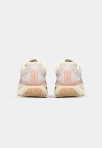 Hardloopschoenen met een gestructureerd, lichtroze mesh bovenwerk, crèmekleurige accenten en een lichtgekleurde, getextureerde rubberen zool.