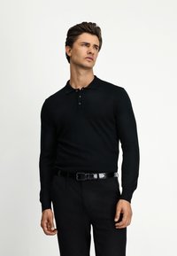 Schwarzes Langarm-Polohemd mit Kragen und Drei-Knopf-Leiste, kombiniert mit schwarzen Hosen. Glattes, tailliertes Material mit klassischem Design.
