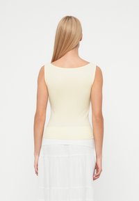 Ανοιχτό κίτρινο ριμπ τοπ με φαρδύ ντεκολτέ και εφαρμοστή γραμμή, με ομαλή υφή και χωρίς ορατά σχέδια ή διακοσμήσεις.
