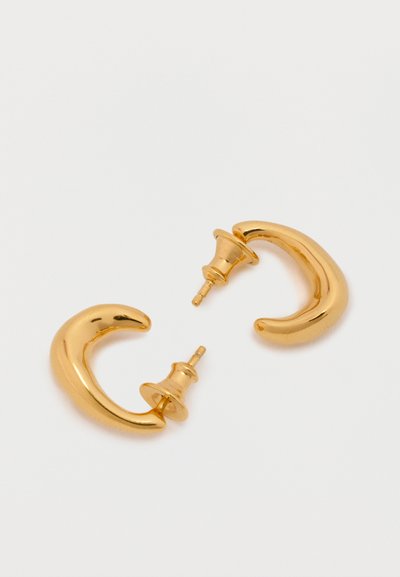 Złote kolczyki w kształcie półksiężyca, z polerowanym wykończeniem i zapięciem na sztyft. Gładka faktura bez dodatkowych wzorów czy akcentów.