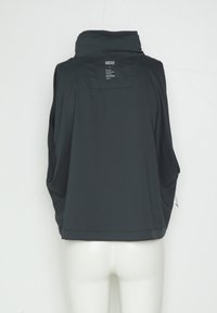 Schwarze ärmellose Jacke mit hohem Kragen, von hinten an einer weißen Schaufensterpuppe gezeigt, mit kleinem weißem Textetikett nahe dem Kragen.