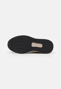 La semelle de la chaussure présente un fond en caoutchouc noir texturé avec des motifs de bande de roulement distincts et une section marquée au centre, conçue pour l'adhérence.