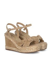 Sandali con zeppa in suede tan, con suola in juta intrecciata, dettaglio anteriore annodato e cinturini alla caviglia regolabili. Superficie testurizzata con accenti lisci.