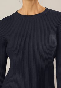 Maglione a coste blu navy con scollo rotondo e maniche lunghe, caratterizzato da un tessuto testurizzato e un design aderente.