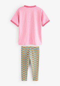 Camisa rosa de manga corta con un cuello en contraste, acompañada de leggins con estampado de arcoíris que presentan semicírculos coloridos.