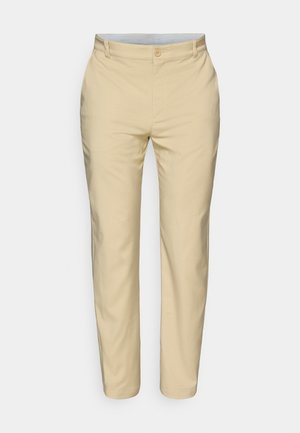 Beżowe spodnie o gładkiej, tkanej fakturze. Posiadają zapięcie na guzik i szlufki na pasek, z tapered nogawkami i eleganckim, dopasowanym wyglądem.