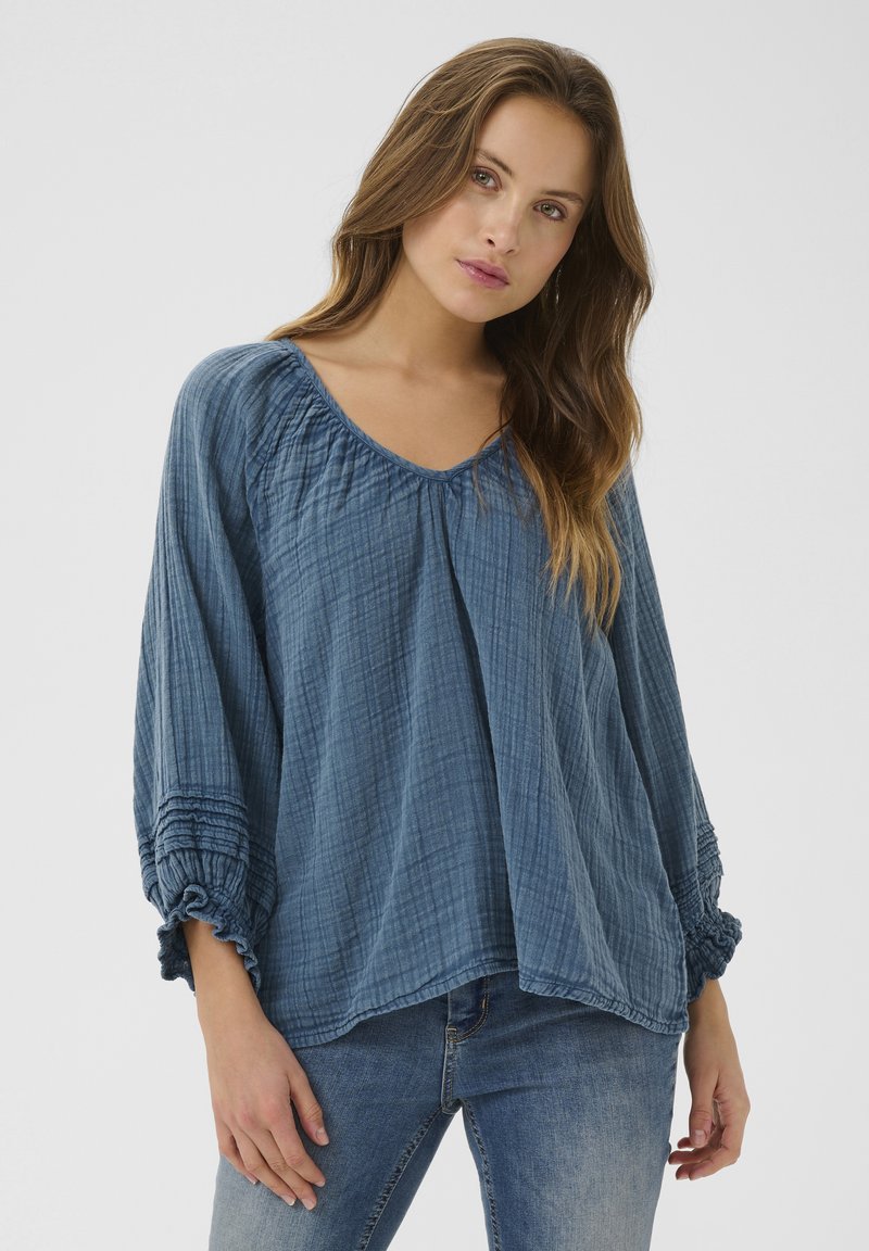 Blaue, locker sitzende Bluse aus strukturiertem Stoff mit Rundhalsausschnitt, gerafften Nähten und elastischen, gerafften Ärmeln.