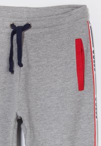 Grijze sweatpants met een tailleband met trekkoord, met een rode zak en zijkanten in blauw en rood. Gemaakt van een katoenmix.
