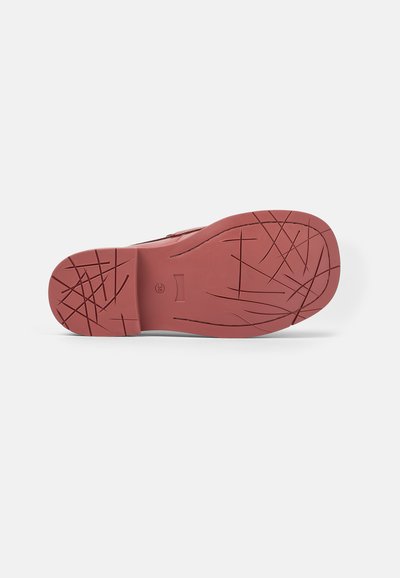 Red rubber shoe sole featuring a textured pattern with grooves and lines for grip, flat shape, and no visible branding or accents.