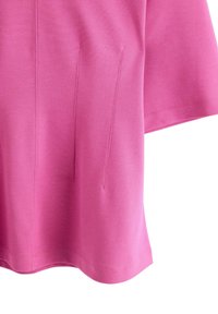 Kort rosa topp av slät tyg, med korta ärmar och subtila sömdetaljer på framsidan, samt rundad nederkant.