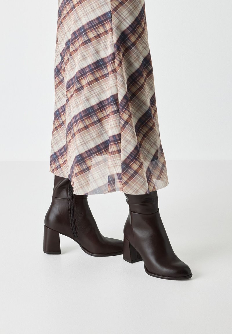 Brown leather ankle boots with a square toe, chunky heel, and visible side zipper. The design features a smooth texture and fitted shaft.