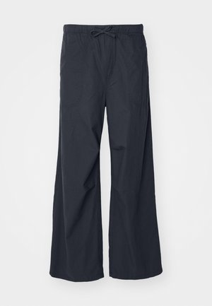 Παντελόνι σε φαρδιά γραμμή από μαύρο ύφασμα, με ελαστική μέση και κορδόνι προσαρμογής, και δύο πλαινές τσέπες. Λείο ύφασμα και χαλαρή σχεδίαση.