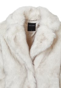 Cappotto in pelliccia sintetica bianco sporco con una consistenza morbida, ampie rever, e un'etichetta che riporta "CALLIOPE" in nero. Tag della taglia: S.