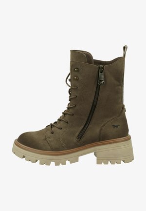 Bruine suède enkellaars met vetersluiting aan de voorkant, een zijrits en een stevige rubberen zool. Decoratieve stiksels en logo-detail aan de zijkant.