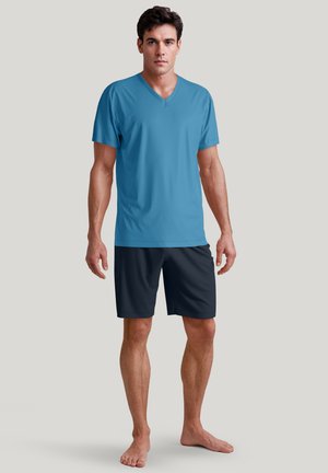 Blauwe V-hals t-shirt gemaakt van lichtgewicht stof, gecombineerd met donkere shorts. Eenvoudig ontwerp, geen patronen, en heeft korte mouwen.