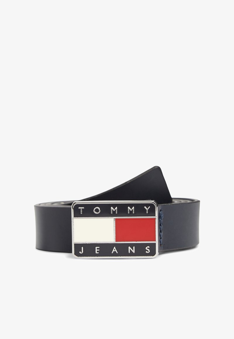 Δερμάτινη ζώνη σε ναυτικό μπλε με ορθογώνιο πόρπη που έχει κόκκινες και λευκές ενότητες, με ανάγλυφο το "TOMMY JEANS" σε ασημένια γράμματα.