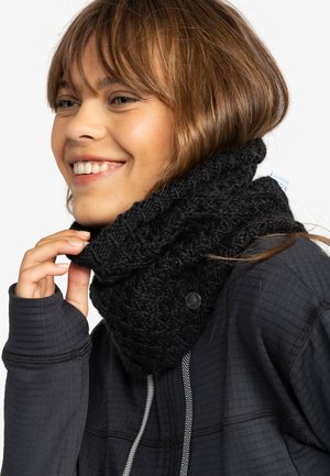 Chale en tricot noir à col roulé avec un design texturé, orné d'une bouton circulaire. Porté par-dessus un haut à manches longues foncé.
