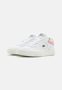 Sneaker bianchi in pelle con un accento rosa testurizzato sul tallone, dotate di lacci, punta rotonda e un logo verde sulla linguetta.