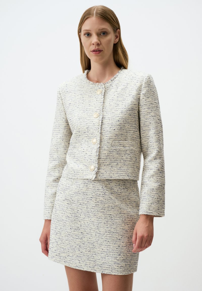 Weiß-blau gesprenkelte Tweedjacke mit Rundhals, kurzer Passform und fünf vorderen Knöpfen, kombiniert mit einem passenden Minirock.